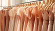 A collection of 'Peach Fuzz' toned bridesmaid dresses hangs uniformly, their cohesive color palette creating an atmosphere of bridal elegance and harmony.
