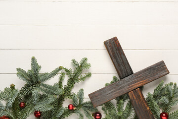 Wall Mural - Cross with fir branches and balls on white wooden background. Christmas story concept