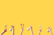 © Pixel-Shot - Hands holding makeup brushes and Christmas decorations on yellow background