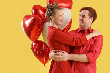 Canvas Print - Young couple with balloons hugging on yellow background. Valentine's Day celebration