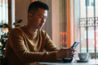 Asian man sitting in coffee shop using smartphone.