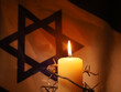 Flag of Israel, barbed wire and burning candle on black background. Holocaust memory day