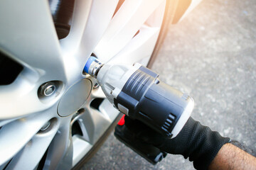 Wall Mural - Car mechanics use cordless impact wrenches to remove car wheel nuts , Car miantenance service concept