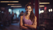 Portrait of smiling young woman standing with arms crossed in a modern fitness center