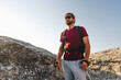 © fotofabrika - Bearded traveler with a backpack and sunglasses on the top of a mountain