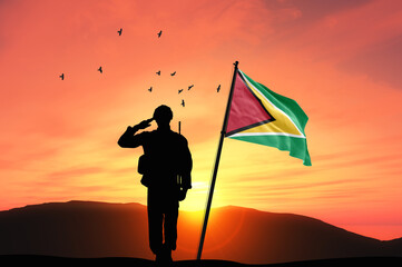 Silhouette of a soldier with the Guyana flag stands against the background of a sunset or sunrise. Concept of national holidays. Commemoration Day.