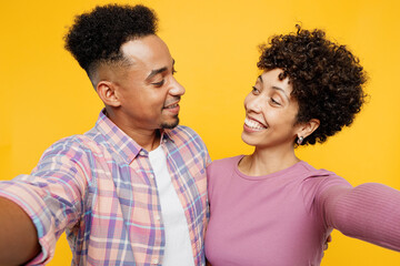 Wall Mural - Close up young couple two friend family man woman of African American ethnicity in casual clothes together do selfie shot pov mobile cell phone look to each other isolated on plain yellow background