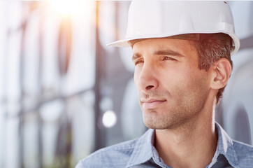 Smiling young unshaven business man in light shirt protective construction helmet.