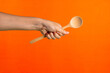 Spoon wooden in hand on orange background