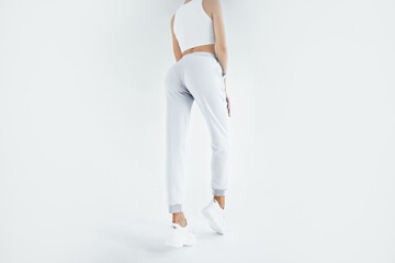 Wall Mural - Back view of a young woman wearing white minimalist sweatpants. Step into Comfort with a Chic White Outfit Perfect for Casual Elegance. Sportwear mock-up. Girl in white pants.