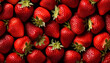 Lots of fresh strawberries swirl around a pile of fresh strawberries seamless background