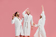 Men, friends in bathrobes and slippers drinking champagne against pink background. Preparation for marriage. Groom's friends. Concept of leisure activity, fun, bachelor party, friendship, spa