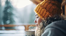 Young woman on a balcony in an holiday resort drinking hot coffee, winter mountains