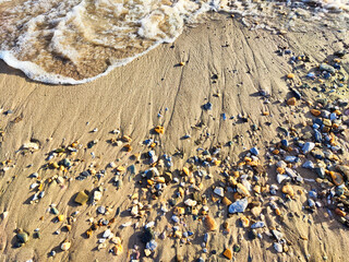 Wall Mural - Yellow sand, pebbles and a transparent wave as a background, texture. Abstract pattern, place for text, copy space