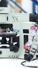 Wall Mural - side view of a young and caucasian scientist looking into a microscope sitting on a laboratory