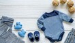 newborn baby boy set blue clothes as bodysuit booties toys on white wooden table top down frame copy space