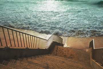 Wall Mural - Stairs to the sandy beach during a storm at sunset