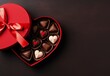 Heart shaped chocolates in a heart shaped box on dark chocolate background.