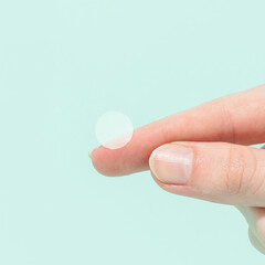 woman holding pimple patch on green background