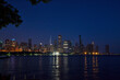 Chicago skyscrapers at night from across water, Lake Michigan in green summer with city lights