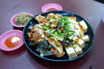 Wall Mural - Chinese food, fried tofu with soy sauce on black plate on wooden table
