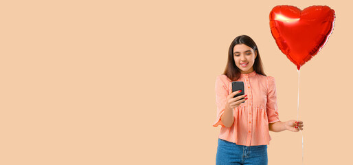 Wall Mural - Young woman with balloon and mobile phone on beige background with space for text