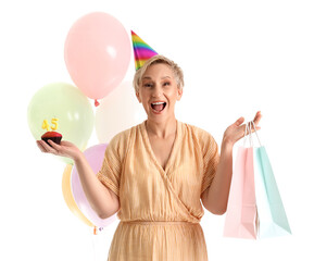 Canvas Print - Happy mature woman with birthday muffin and bags on white background