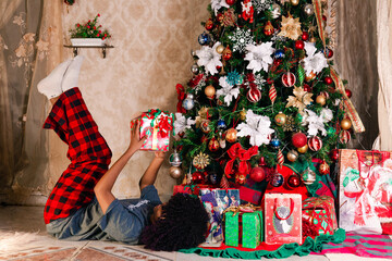 Wall Mural - Girl with present laying in the floor next to the christmas tree