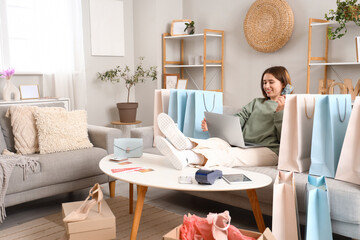 Wall Mural - Young woman with credit card and laptop shopping online at home