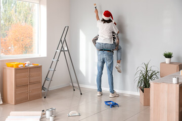 Canvas Print - Young couple with Santa hats painting wall during repair in their new house, back view