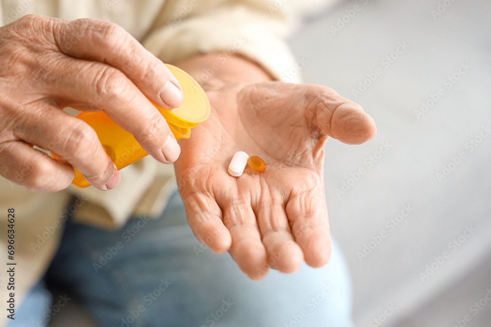 Senior woman taking pills at home, closeup