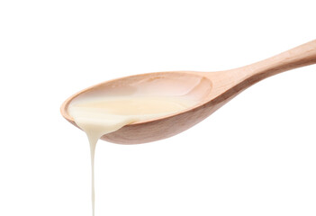 Wall Mural - Pouring condensed milk from wooden spoon isolated on white
