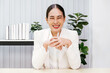 © artitwpd - Portrait of successful Asian businesswoman inside the office looking at the camera, talking on a video call with colleagues, gesturing and smiling during an online meeting with customers. Influencer.