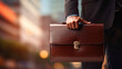 Detail of a businessman holding a leather briefcase.