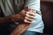 A man with a bruised arm sitting on a couch. This image can be used to depict injury, pain, recovery, or medical concepts
