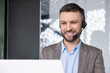 © Liubomir - Businessman in business suit with headset phone for video call smiling typing on laptop keyboard, online customer service worker at workplace inside office.