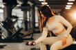 Strong woman pumping iron in a gym with the help of three-kilo dumbbell in her hand