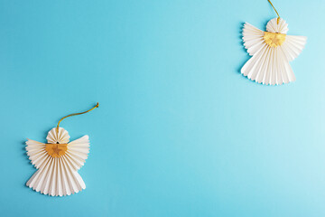 Two Christmas paper angels on light blue background. Holiday concept. Top view, flat lay, copy space