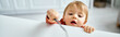 © LIGHTFIELD STUDIOS - cute little baby girl in cozy orange sweater trying to reach out some breakfast on table, banner
