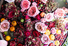 Red Roses, Hydrangea, Reddish Cranberries, Chrysanthemums, Tangerines In Water In A Tin Basin As A Flower Shop Decoration. Composition In Red, Purple Christmas Colors