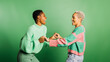 © Jordi Salas - Two young cheerful women wearing green clothes and dancing in a studio with a green background.