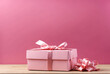 Pink gift box with pink ribbon on the pink background