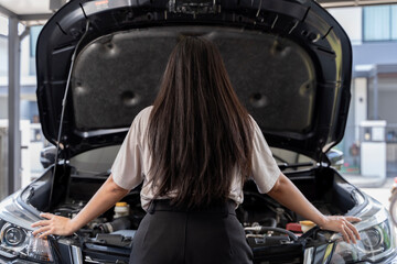 Wall Mural - A young Asian woman has a broken car in the middle of the way and must call a mechanic to fix it. Portrait of young woman standing in front of her broken car.