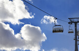 Fototapeta Góry - Chair-lift and blue sky with sunlight clouds