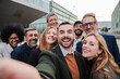 © Jose Calsina - Big group of business people smiling taking a selfie portrait toguether. Crowd of business people looking at camera. Startup corporate team having fun. Happy well dressed executive firm partners. High