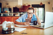 © Geber86 - Smiling woman checking smartphone while working at home