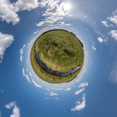 green tiny planet in blue sky with beautiful clouds. Transformation of spherical panorama 360 degrees. Spherical abstract aerial view. Curvature of space.