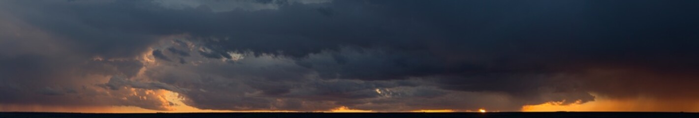 Landscape at sunset. A thunderstorm is approaching the village. Tragic gloomy sky. Panorama.