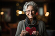 Senior lovely woman holds in hands a paper heart, during celebrating St. Valentines Day
