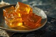 orange jelly cubes in a plate on a dark background. Selective focus.
